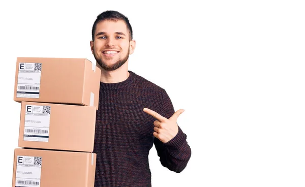 Joven Hombre Guapo Sosteniendo Paquete Entrega Sonriendo Feliz Señalando Con — Foto de Stock