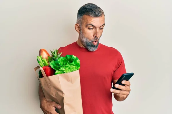 Hombre Guapo Mediana Edad Sosteniendo Bolsa Comestibles Usando Teléfono Inteligente —  Fotos de Stock
