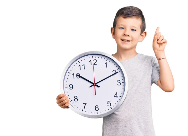 Cute Blond Kid Holding Big Clock Surprised Idea Question Pointing — Stock Photo, Image