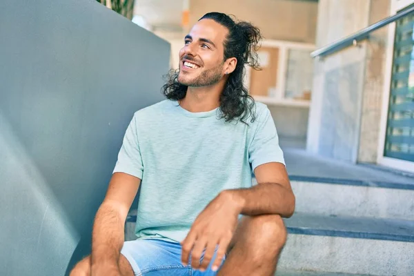 Jovem Hispânico Sorrindo Feliz Olhando Para Lado Sentado Nas Escadas — Fotografia de Stock