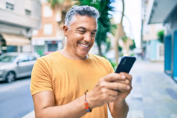 Medelålders Gråhårig Man Ler Glad Med Smartphone Promenader Gatan Staden — Stockfoto