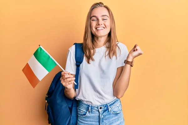 Hermosa Mujer Rubia Estudiante Intercambio Sosteniendo Bandera Irlanda Gritando Orgulloso —  Fotos de Stock