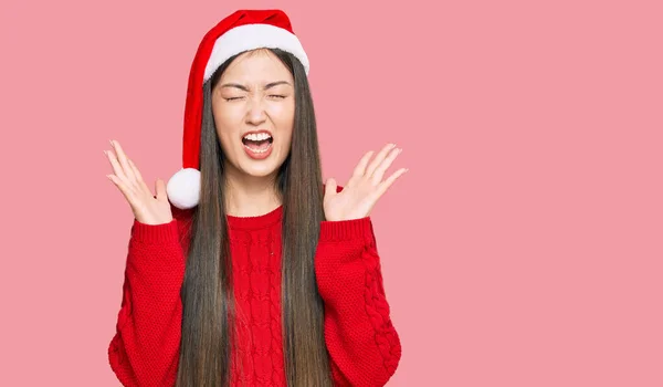 腕を上げ 興奮叫んで目を閉じて成功のために狂気と狂気を祝うクリスマスの帽子をかぶって若い中国の女性 勝者のコンセプト — ストック写真