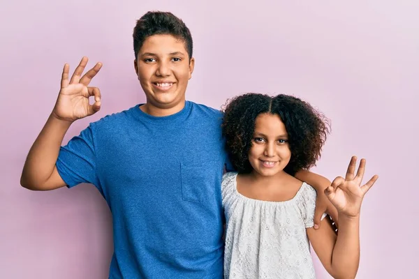 手や指でOkサインをしながら積極的に笑顔でカジュアルな服を着ている弟と妹の若いヒスパニック系の家族 成功した表現 — ストック写真