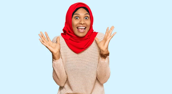 身穿传统伊斯兰头巾的年轻的非洲裔美国女人兴奋地举起双臂 睁开眼睛尖叫 庆祝胜利 获奖者概念 — 图库照片