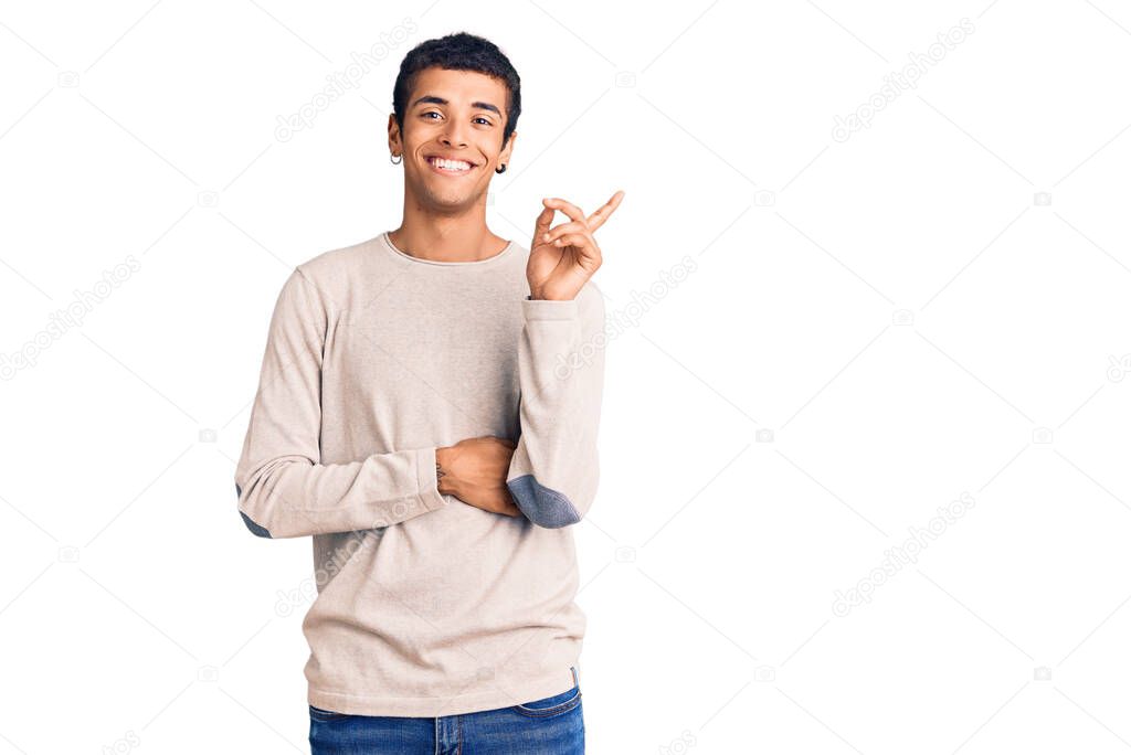 Young african amercian man wearing casual clothes with a big smile on face, pointing with hand and finger to the side looking at the camera. 