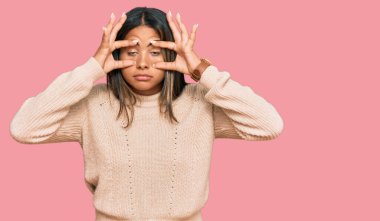 Kışın yün kazak giyen genç Latin kız parmaklarıyla gözlerini açmaya çalışıyor, uykulu ve yorgun sabah yorgunluğu çekiyor. 