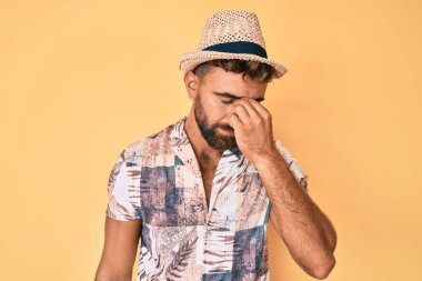 Yaz şapkası takan genç İspanyol adam yorgun burnu ve gözleri ovuşturup yorgun ve baş ağrısı çekiyor. Stres ve hüsran kavramı. 