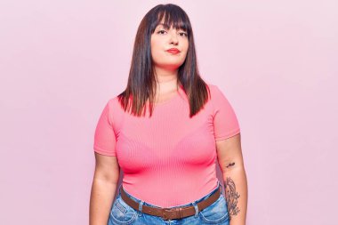 Gündelik kıyafetler giyen genç ve iri yarı bir kadın. Yüzünde ciddi bir ifadeyle rahatlamış. Basit ve doğal bir şekilde kameraya bakıyorsun.. 