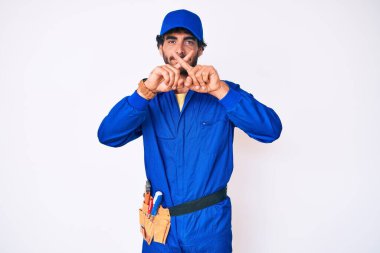 Kıvırcık saçlı ve ayı gibi giyinen yakışıklı genç adam. Tamirci üniforması, reddedilme ifadesi. 