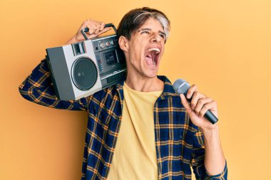 Genç İspanyol adam mikrofon ve teyp kullanarak şarkı söylüyor kızgın ve öfkeli çığlıklar atıyor öfkeyle bağırıyor, öfkeyle yukarı bakıyor. 