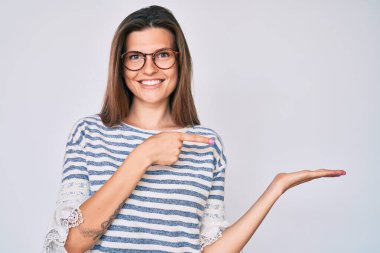 Güzel beyaz kadın, günlük kıyafetler ve gözlük takıyor kameraya hayret ediyor ve gülümsüyor.. 