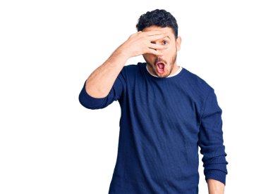 Gündelik kıyafetler giyen genç İspanyol adam şok içinde yüzünü ve gözlerini kapayarak utanmış ifadesiyle parmaklarından bakıyor.. 