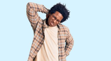 Yakışıklı Afro saçlı, sıradan kıyafetler giyen ve gözlüklü boynu ağrıyan, elleriyle boynuna dokunan, kas ağrısı çeken Afro-Amerikan bir adam. 