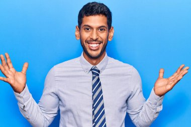 İş kıyafetleri içindeki genç Latin adam zaferi mutlu bir gülümsemeyle ve kazanan yüz ifadesiyle kutluyor. 