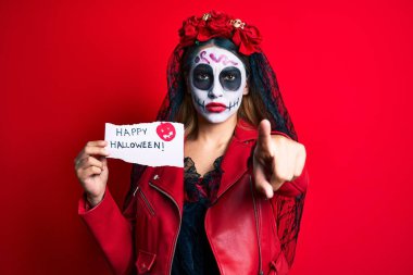 Ölü kostümü giymiş bir kadın elinde mutlu bir cadılar bayramı kağıdıyla kamerayı işaret ediyor ve sen kendinden emin bir şekilde ciddi görünüyorsun. 