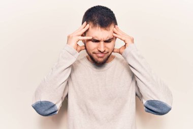 Genç yakışıklı bir adam gündelik kazak giyiyor. Baş ağrısı, çaresiz ve stresli. Çünkü acı ve migren ağrısı var. Eller başının üstünde.. 