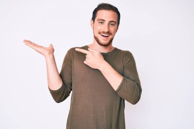 Gündelik kıyafetler giyen genç yakışıklı adam kameraya hayret ediyor ve gülümsüyor.. 