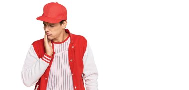 Beyzbol üniforması giyen yakışıklı beyaz adam diş ağrısı ya da diş ağrısı yüzünden ağızlarına acı dolu bir ifadeyle dokunuyor. dişçi 