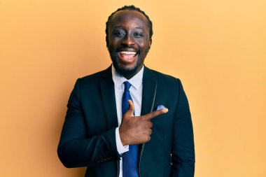 Yakışıklı, genç, siyah takım elbiseli ve kravatlı. Gülümseyen, el ve parmak uçlarında. 