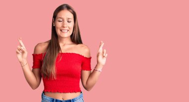 Genç ve güzel İspanyol bir kadın günlük kıyafetler giyip umut ve gözlerin kapalı bir şekilde parmaklarını çaprazlayarak gülümsüyor. Şans ve batıl inançlar. 