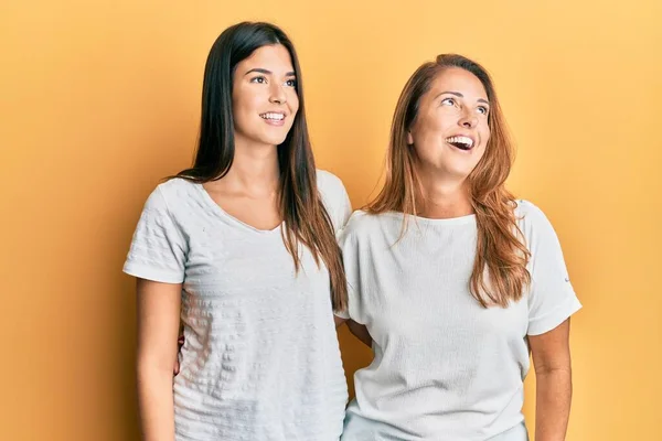 母親と娘の顔に笑顔で横に離れて見てカジュアルな白いTシャツを着てのヒスパニック系の家族は 自然な表情 自信を持って — ストック写真