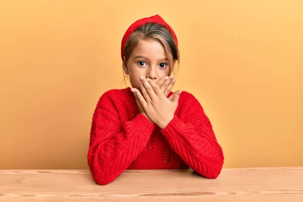 Niña Hermosa Con Ropa Casual Sentada Mesa Impactada Cubriendo Boca — Foto de Stock