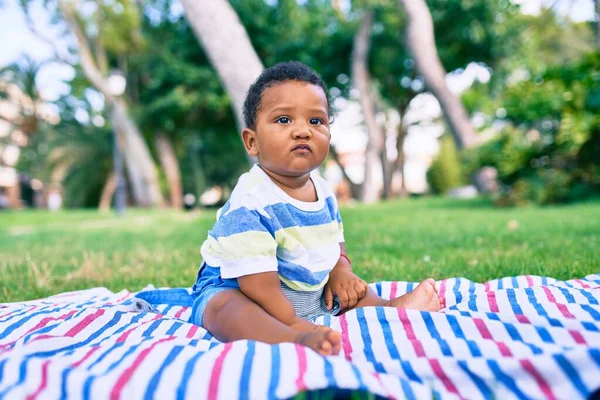 公園で草の上に座っている愛らしいアフリカ系アメリカ人のぽっちゃり幼児 — ストック写真