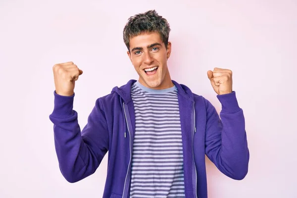 年轻英俊的男子穿着休闲的紫色运动衫 自豪地尖叫着 高举双臂庆祝胜利和成功 — 图库照片