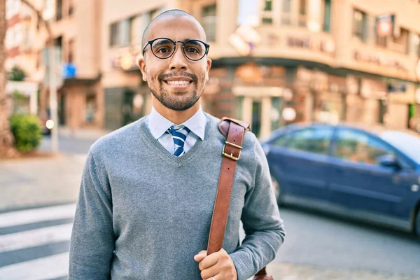 Genç Afrikalı Amerikalı iş adamı gülümseyerek şehirde mutlu bir şekilde yürüyor..