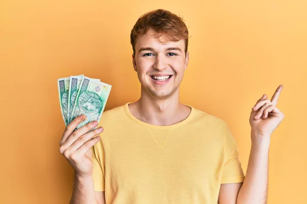 Joven Hombre Caucásico Sosteniendo Billetes Zloty Pulido Sonriendo Feliz Señalando —  Fotos de Stock