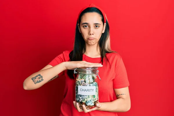 Mujer Hispana Joven Sosteniendo Frasco Caridad Con Dinero Deprimido Preocupación —  Fotos de Stock
