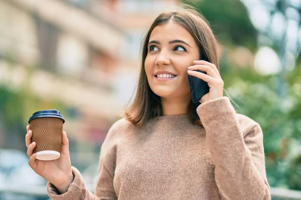 Genç İspanyol kadın akıllı telefonda konuşuyor parkta kahve içiyor..