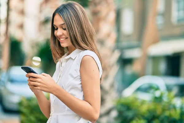 美しいですラテンティーン女の子笑顔幸せ使用してスマートフォンで市 — ストック写真