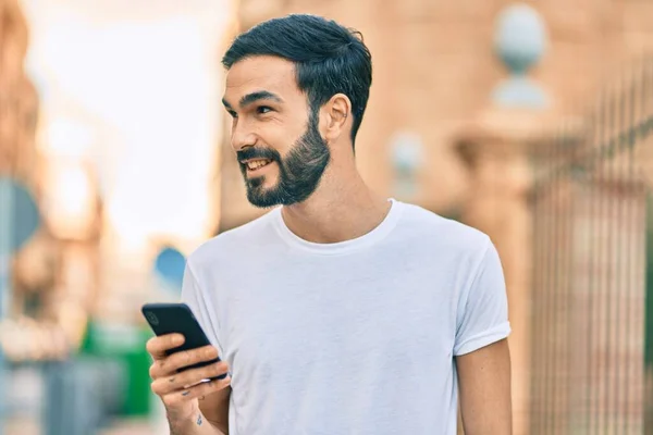 Joven Hombre Hispano Sonriendo Feliz Usando Smartphone Ciudad —  Fotos de Stock