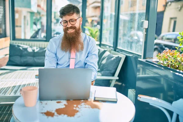 若い赤毛のビジネスマンは コーヒーショップのテラスに座ってノートパソコンを使用して幸せな仕事を笑って — ストック写真