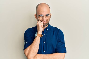 Gündelik kıyafetler ve gözlük takan genç İspanyol adam çapraz kollu depresyondan sıkılmış ve yorgun göründüğünü düşünüyor.. 