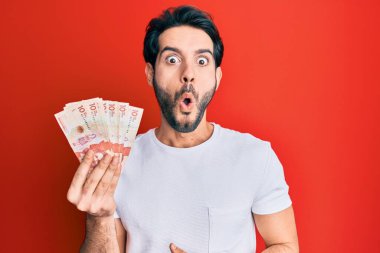 Genç İspanyol adam elinde 10 Kolombiya pezosu tutuyor. Korkmuş ve şaşkın bir şekilde ağzı açık kalmış, inançsız bir yüz. 