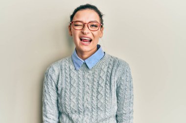 Gündelik kıyafetler ve gözlük takan genç beyaz kadın kameraya seksi bir ifadeyle bakıyor, neşeli ve mutlu bir yüzle.. 