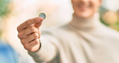 Genç İspanyol gülümseyen adam şehirde 1 Euro 'luk bozuk para tutuyor..