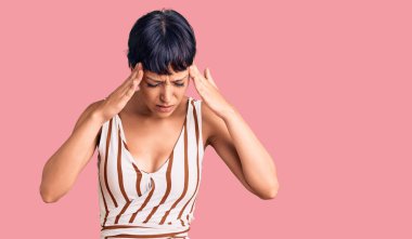 Kısa saçlı genç esmer kadın stresten kafasında ağrı olduğu için elleri kafasında olan yazlık kıyafetler giyiyor. migren ağrısı. 