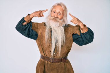 Gri saçlı, uzun sakallı, Viking kostümlü yaşlı bir adam. İki eliyle kafasını gösteren geleneksel bir gülümseme. Harika bir fikir ya da düşünce, iyi bir hafıza. 