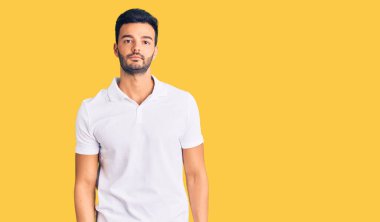 Gündelik kıyafetler giyen genç, yakışıklı İspanyol adam yüzünde ciddi bir ifadeyle rahatlamış. Basit ve doğal bir şekilde kameraya bakıyorsun.. 