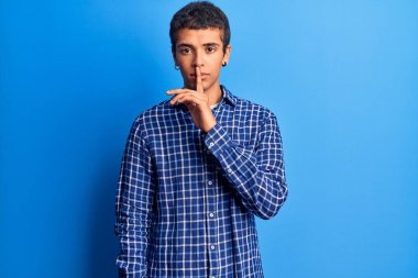 Gündelik giysiler giymiş genç Afro-Amerikan bir adam parmakları dudaklarında sessiz olmak istiyor. sessizlik ve gizli konsept. 