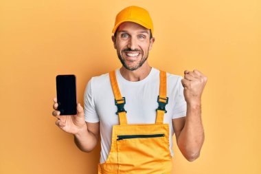 Becerikli üniformalı genç bir adam akıllı telefon ekranında gururla bağırıyor zaferi ve başarıyı kutluyor. 