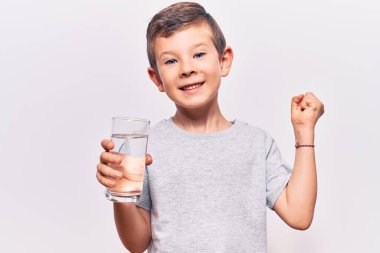 Sevimli sarışın çocuk bir bardak su içiyor gururla bağırıyor zaferi kutluyor ve başarıyı kollarını kaldırarak kutluyor. 