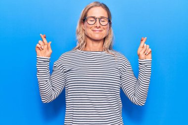 Orta yaşlı, beyaz, çizgili süveter giyen, gözlüklü, umut dolu ve gözleri kapalı gülümseyen sarışın bir kadın. Şans ve batıl inançlar. 