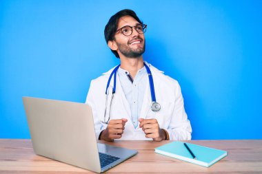 Yakışıklı, doktor üniforması giyen, klinikte çalışan, profil pozu veren, doğal yüzlü ve kendine güvenen bir adam.. 