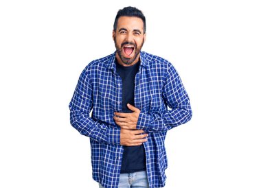 Gündelik kıyafetler giyen genç İspanyol adam gülümseyerek kahkahalarla gülüyor çünkü elleri vücutta olan komik, çılgın bir şaka.. 