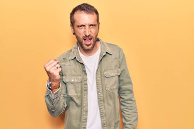 Genç, yakışıklı bir adam, kızgın ve kızgın. Öfkeyle bağırırken yumruğunu sallıyor ve öfkeleniyor. öfke ve agresif konsept. 